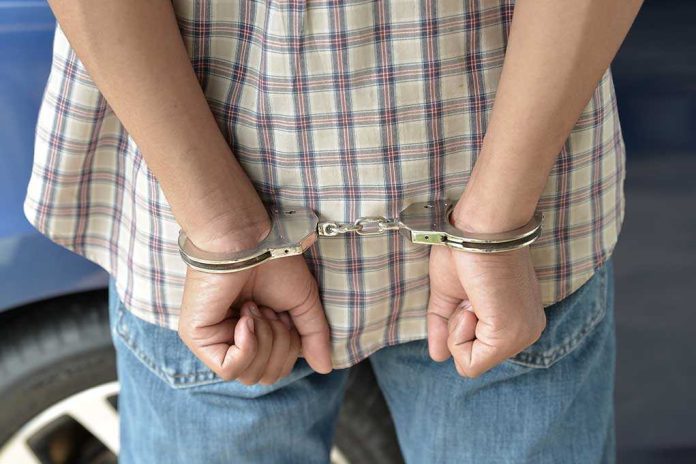 shutterstock_215366989.jpg A person in handcuffs viewed from behind wearing a plaid shirt and denim jeans