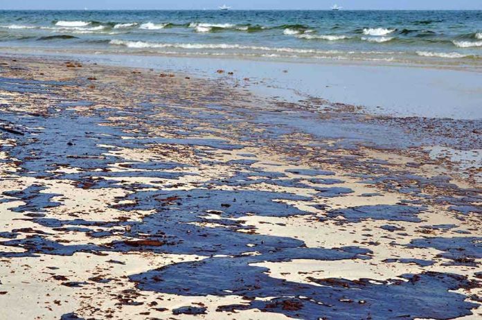 shutterstock_55817806.jpg Oil spill on a sandy beach with waves in the background