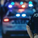 Police officer with patrol car and flashing lights