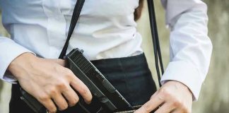 Person placing gun into a handbag.