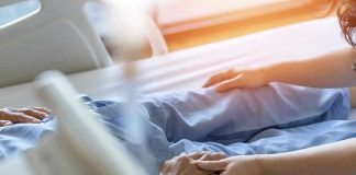 Hospital patient holding visitor's hand reassuringly.