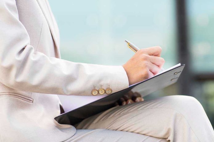 298063787 Person in beige suit writing on a clipboard