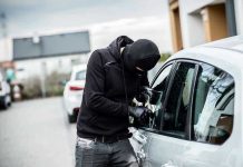 Person in black breaking into a car.