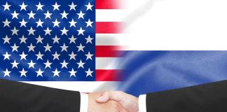 Hands shaking in front of USA and Russia flags
