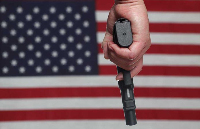 shutterstock_141984028.jpg A hand holding a gun in front of an American flag