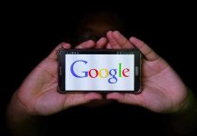 Hands holding smartphone displaying Google logo.