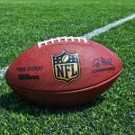 An NFL football resting on a green grass field