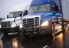 Trump’s Truckers PROFITING  — Here’s How Two trucks driving on a wet road.
