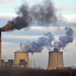 Industrial plant emitting black smoke into the sky.