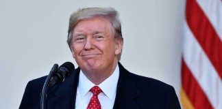 Man in suit and tie speaking at podium.