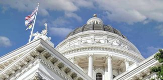 Capitol building dome and flags under a blue sky.
