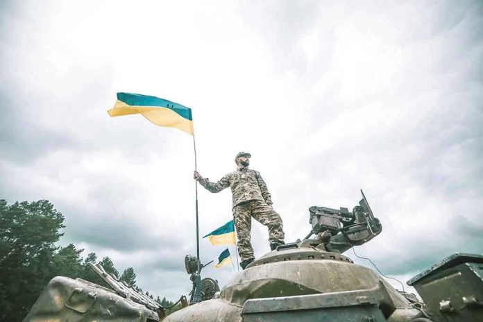 723045559 Soldier on tank holding Ukrainian flag.