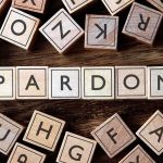 Trump FREES Billion-Dollar Scammer After Two Weeks Wooden letter blocks arranged to spell 'PARDON' on a wooden surface