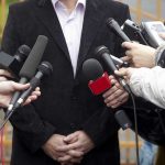 A group of microphones surrounding a person at a press conference