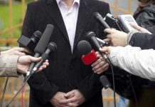 A group of microphones surrounding a person at a press conference