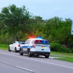 Driver FLEES Cops – Kills 4 Bystanders Police car with flashing lights pulling over a white vehicle beside a speed limit sign
