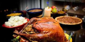 A beautifully roasted turkey on a festive table surrounded by side dishes and decorations