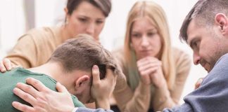 Group comforting a distressed person with hand on shoulder.