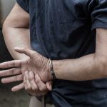 ICE Arrests Set to SKYROCKET – Unprecedented Raids Loom Person in handcuffs with hands behind back.