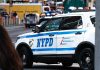 Unfit Cops Keep Jobs – Standards Crumble NYPD police car on a city street scene.