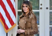 Trump’s Ukraine Deal IMPLODES – Melania Steps In Woman in brown coat beside American flag.