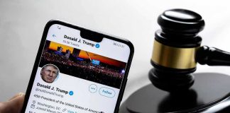 Smartphone displaying Twitter profile near a judges gavel.