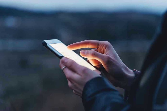 585973055 Person using a smartphone at dusk.