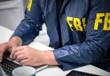 FBI Kneeling Stunt BACKFIRES — Massive Lawsuit Erupts Person in FBI jacket typing on a laptop.