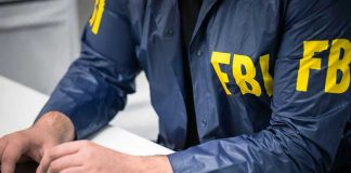FBI Kneeling Stunt BACKFIRES — Massive Lawsuit Erupts Person in FBI jacket typing on a laptop.