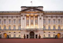 Front view of Buckingham Palace with illuminated facade and British flag