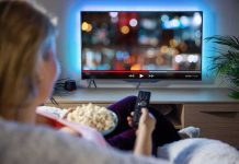 Netflix’s Deal in Jeopardy: Paramount Strikes Hard Person sitting on a couch watching a movie on a TV with popcorn in hand