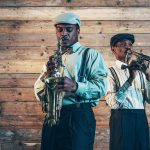 Musician’s Political Stunt RUINS Holiday Tradition Two jazz musicians playing saxophone and trumpet against a wooden wall