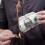 15 Million Debt: Biden’s Hidden Crisis A person holding a burning dollar bill with a match in the other hand