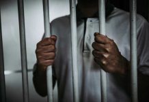 Former CNN Anchor ARRESTED – Shocking Federal Charges Person holding jail cell bars tightly.