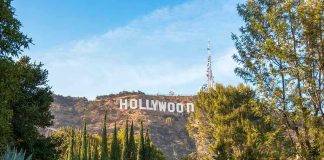 Hollywood sign on hill surrounded by trees and buildings.