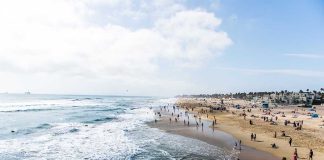 Crowded beach with waves and people enjoying sun.