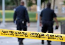 Chilling 911 Call: Child Saves Siblings From Shooter Police officers walking past caution tape at a crime scene