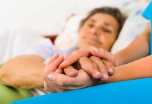 Shocking Truth Behind Super Agers’ Sharp Minds A caregiver holding the hands of an elderly patient in a hospital bed