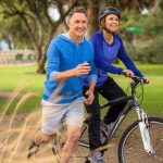 A couple enjoying outdoor exercise, with one riding a bike and the other jogging alongside