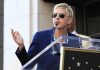 Ellen DeGeneres’s FAKE Exodus—The Truth Finally Revealed A woman in sunglasses speaking at a podium during an outdoor event