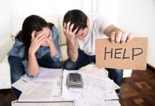 A distressed couple surrounded by paperwork, with one holding a sign that says HELP