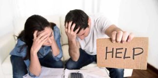A distressed couple surrounded by paperwork, with one holding a sign that says HELP