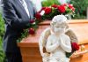 Statue of angel in front of coffin with roses.