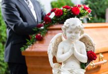 Statue of angel in front of coffin with roses.