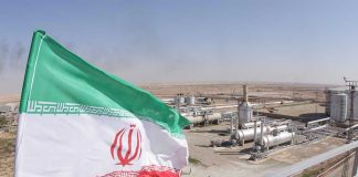 Trump’s Iran Ultimatum FREEZES Midday Iranian flag near an industrial gas refinery.