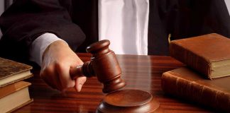 158-Year Moonshine Ban CRUMBLES A judges hand holding a gavel over a wooden desk with law books