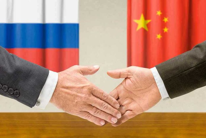 Two hands shaking in front of two flags.
