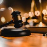 Judge’s Steamy Chambers, Her Affair Exposed Gavel on wooden table with scales in background.