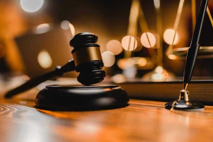 2291220799 Gavel on wooden table with scales in background.