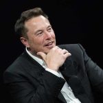 Stunning TECH Verdict: Musk Loses To OpenAI Man in suit smiling, resting chin on hand.